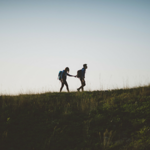 couple holding hands while walking on trail