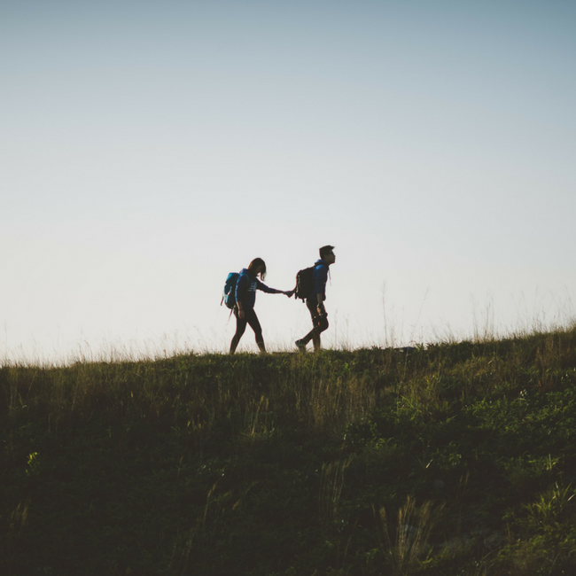 couple holding hands while walking on trail