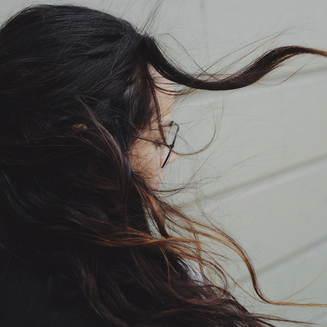 brunette woman looking down hair blowing in wind