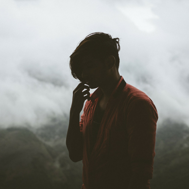 man thinking at the top of a mountain