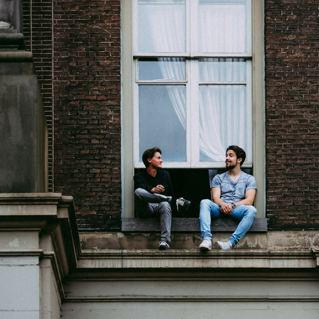 two friends talking on roof by window