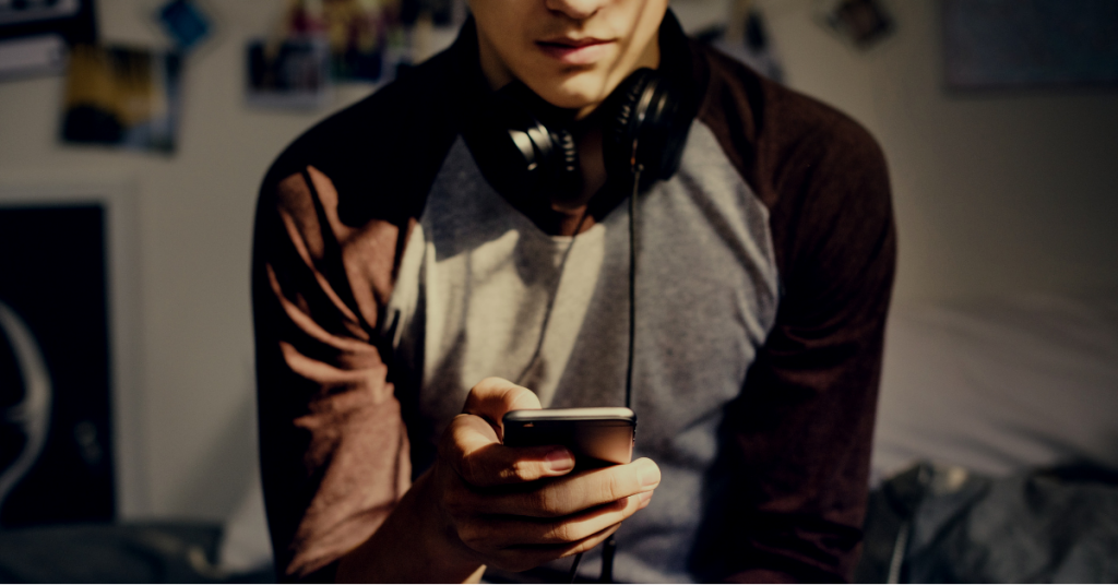 teen sitting on bed with smartphone