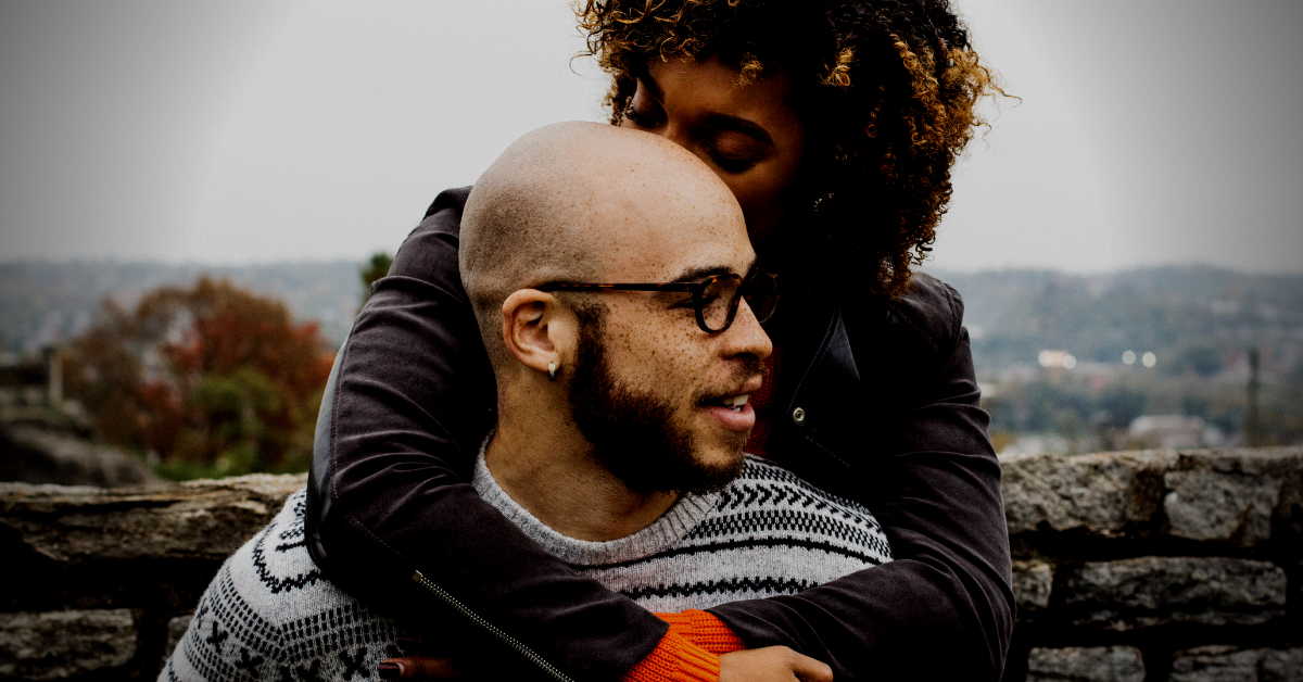 couple hugging outside by stone wall