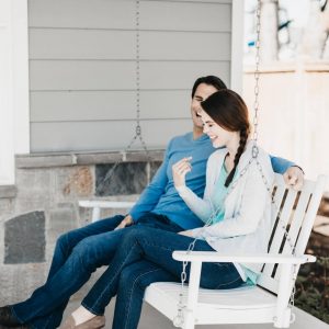 husband and wife laughing on porch swing