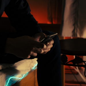 hands of man on cell phone in dark room