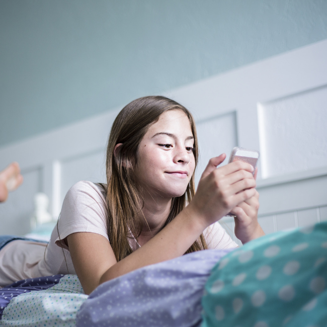 Young girl using phone in bedroom