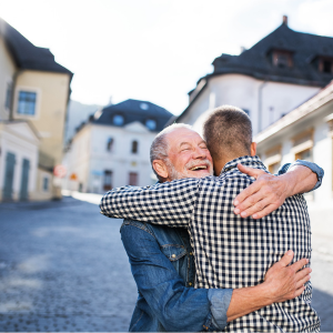 dad hugging adult son on street