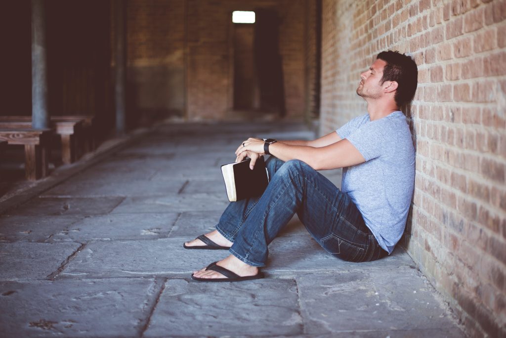 man sitting on floor by brick wall