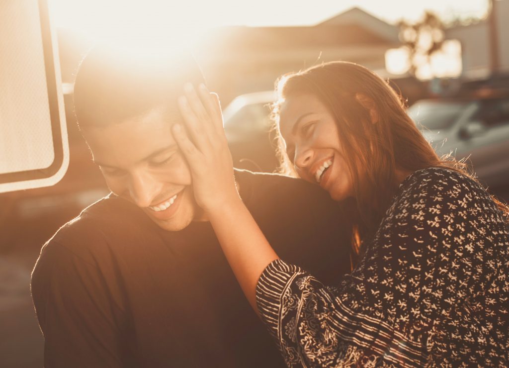 couple laughing together by car