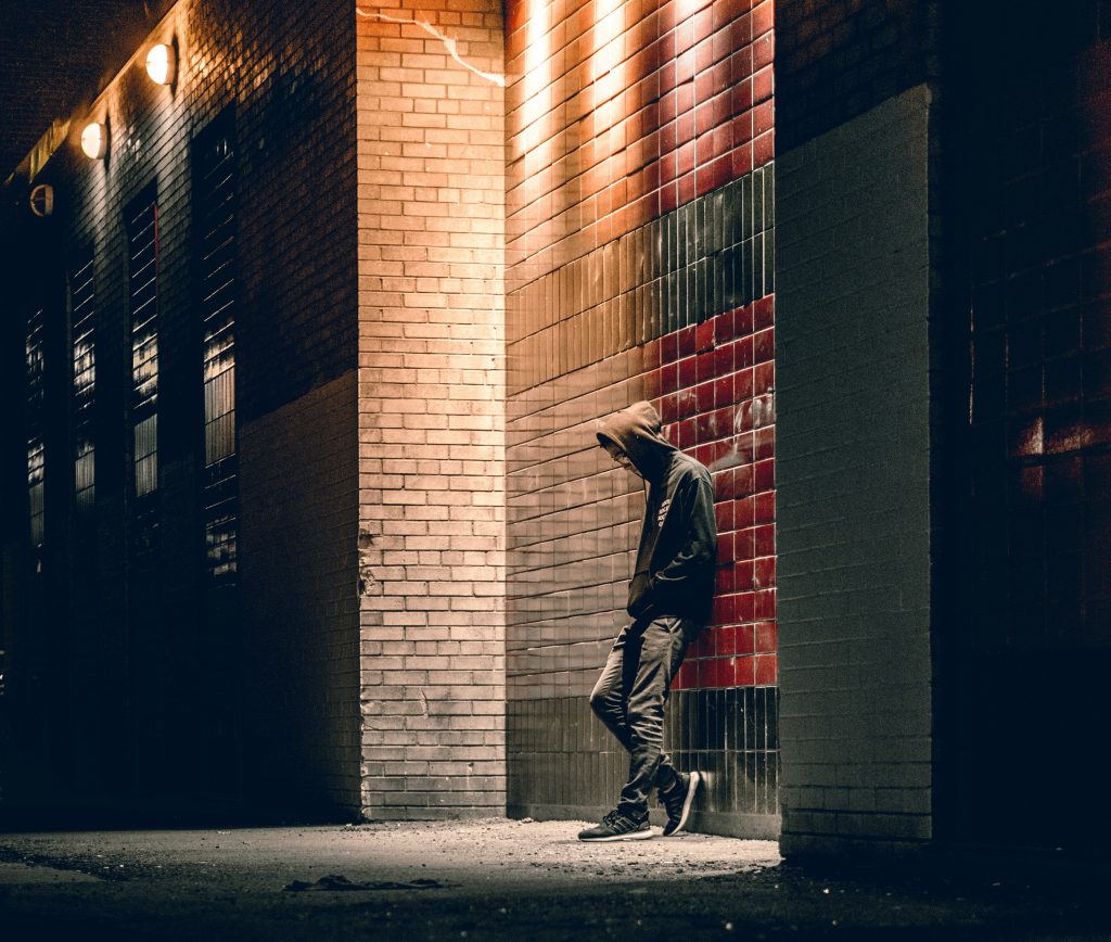man leaning against brick wall outside