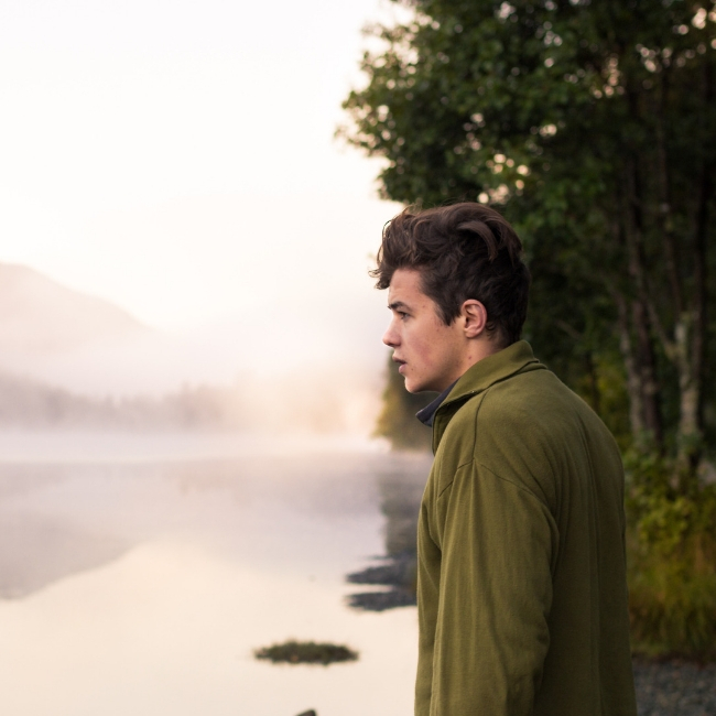 young man looking over foggy pond