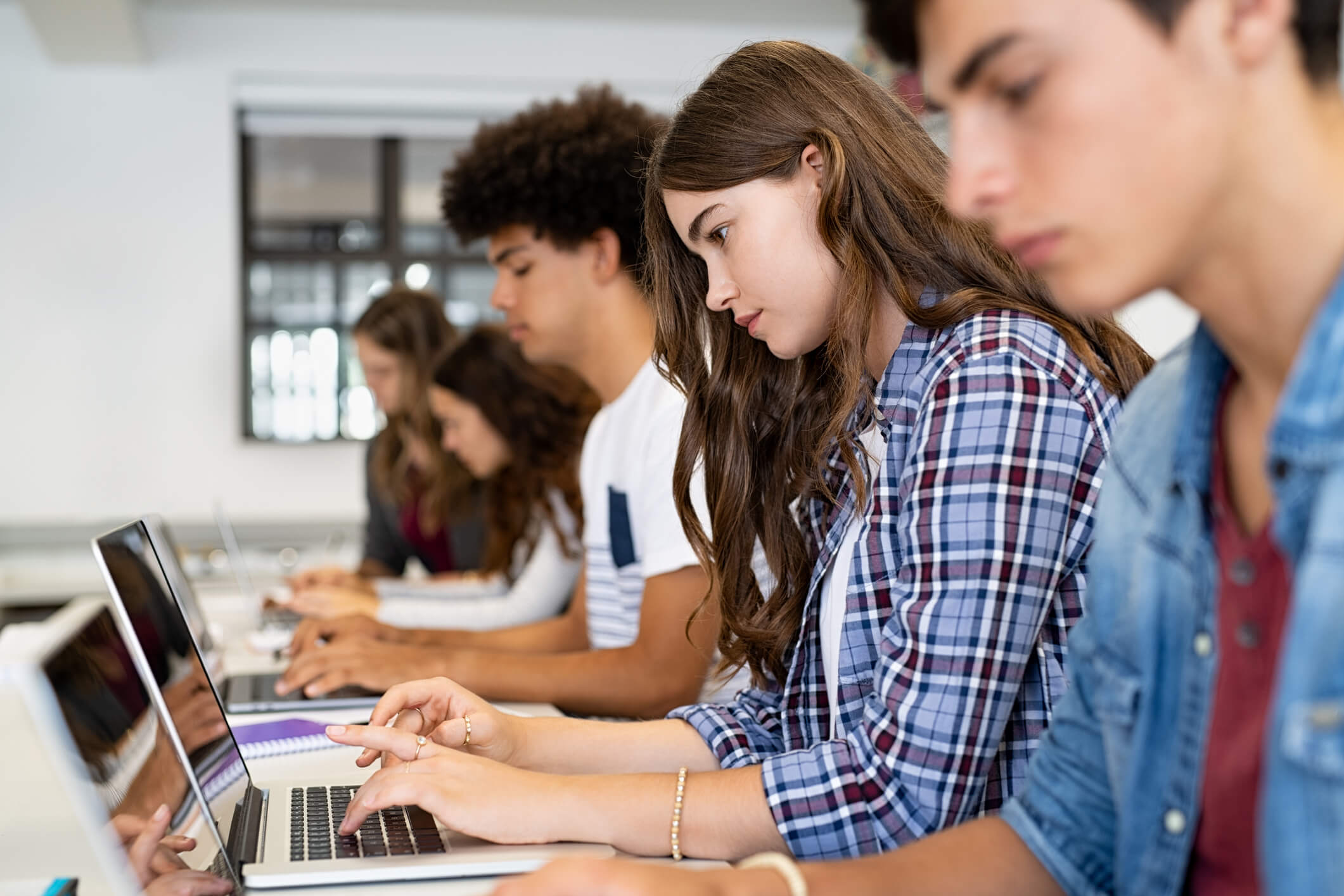 Teenagers in a classroom using laptops.