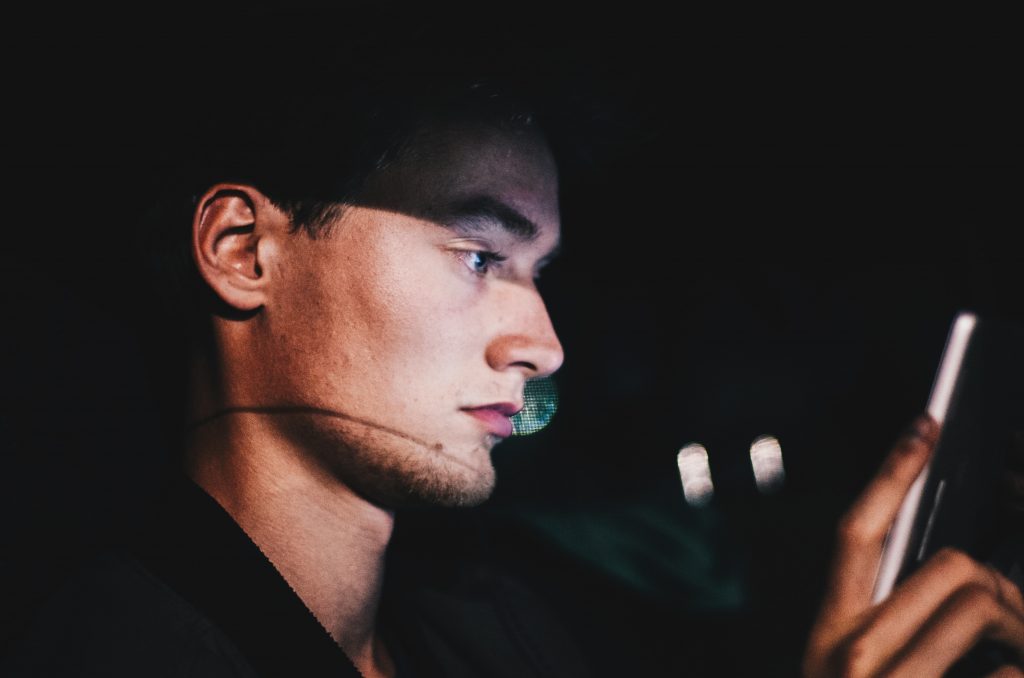 man staring at phone in dark