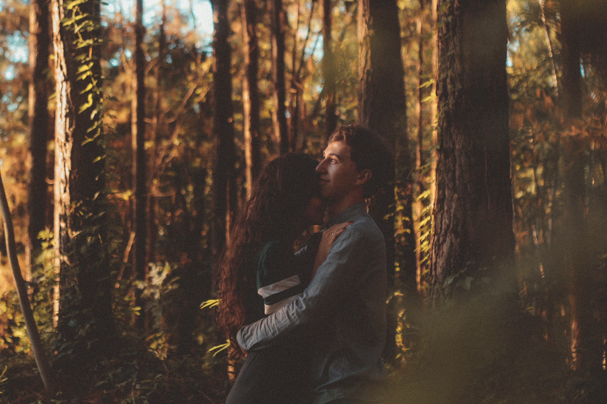young couple hugging in woods