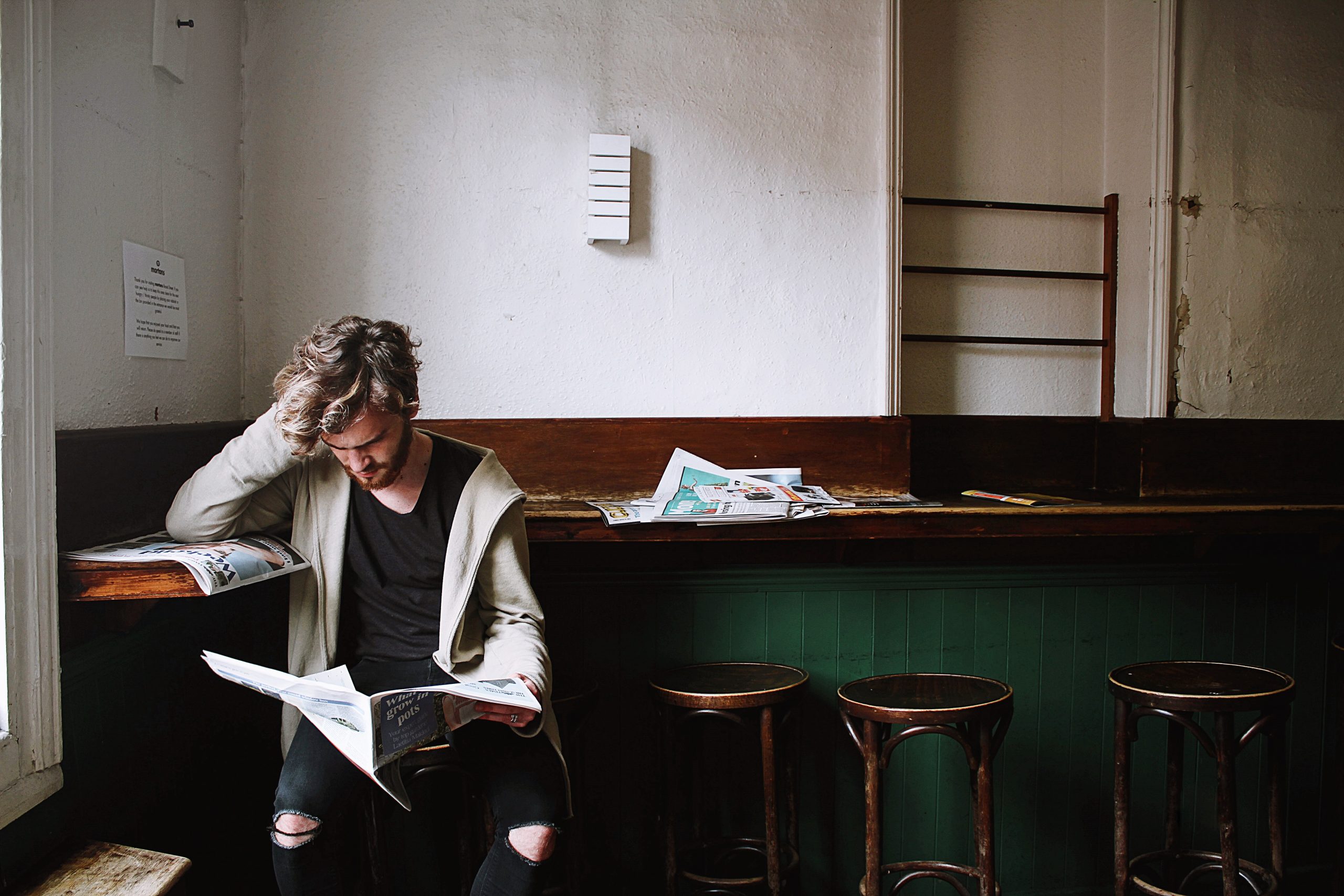 man reading newspaper at bar