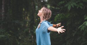 woman with open arms in woods