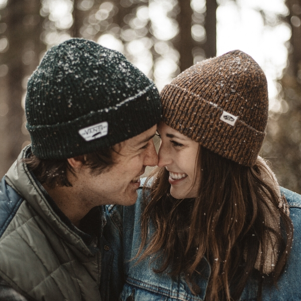 happy couple with beanies on outside in snow