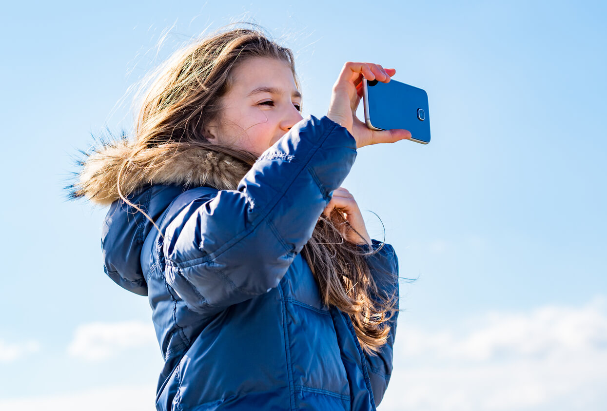 young girl in a winter jacket with a phone