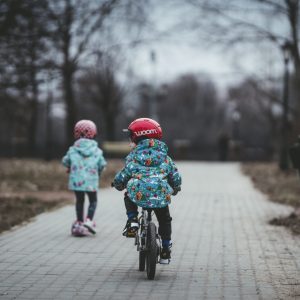 two kids on scooter and bike outside