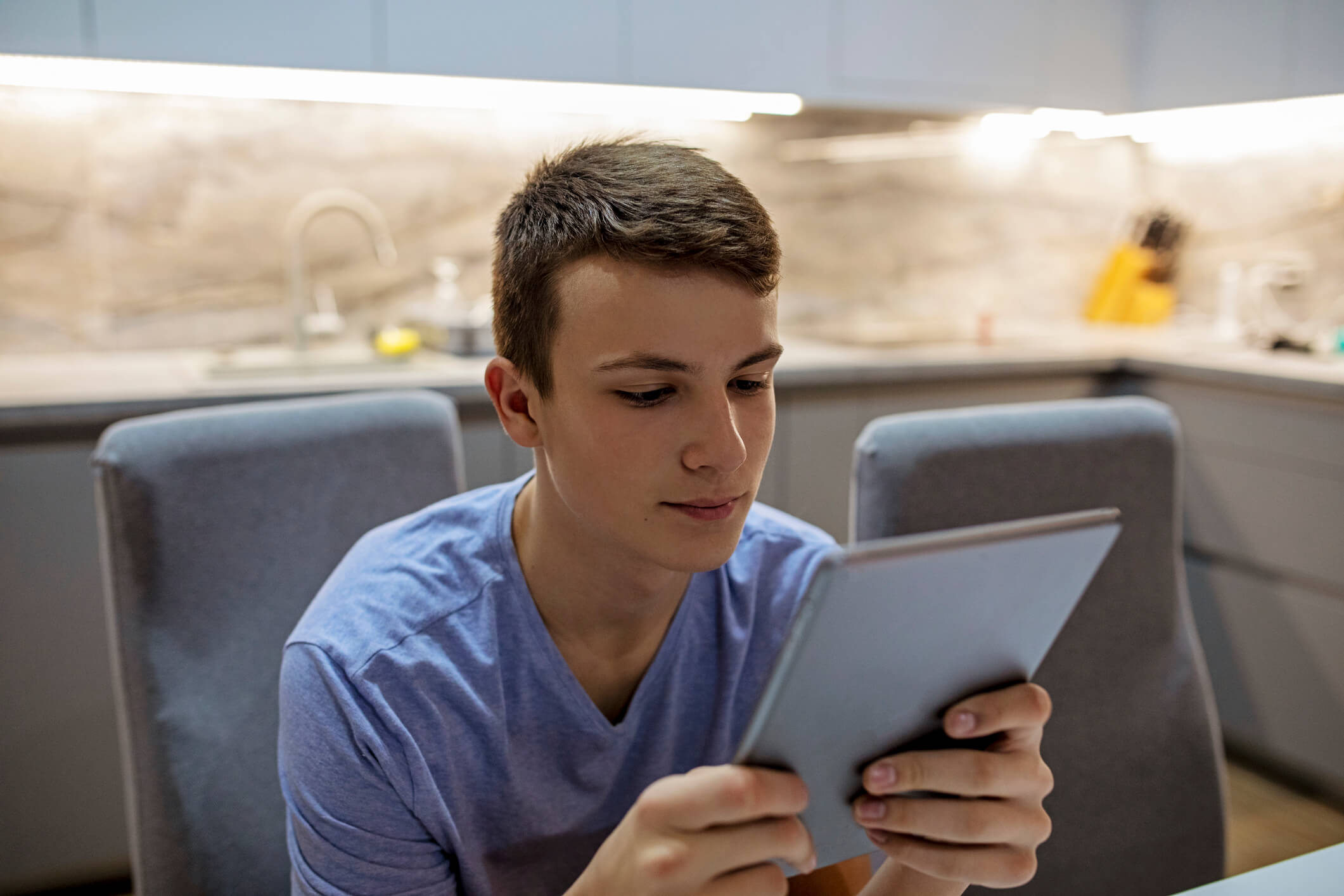 A teenage boy looking at a tablet.