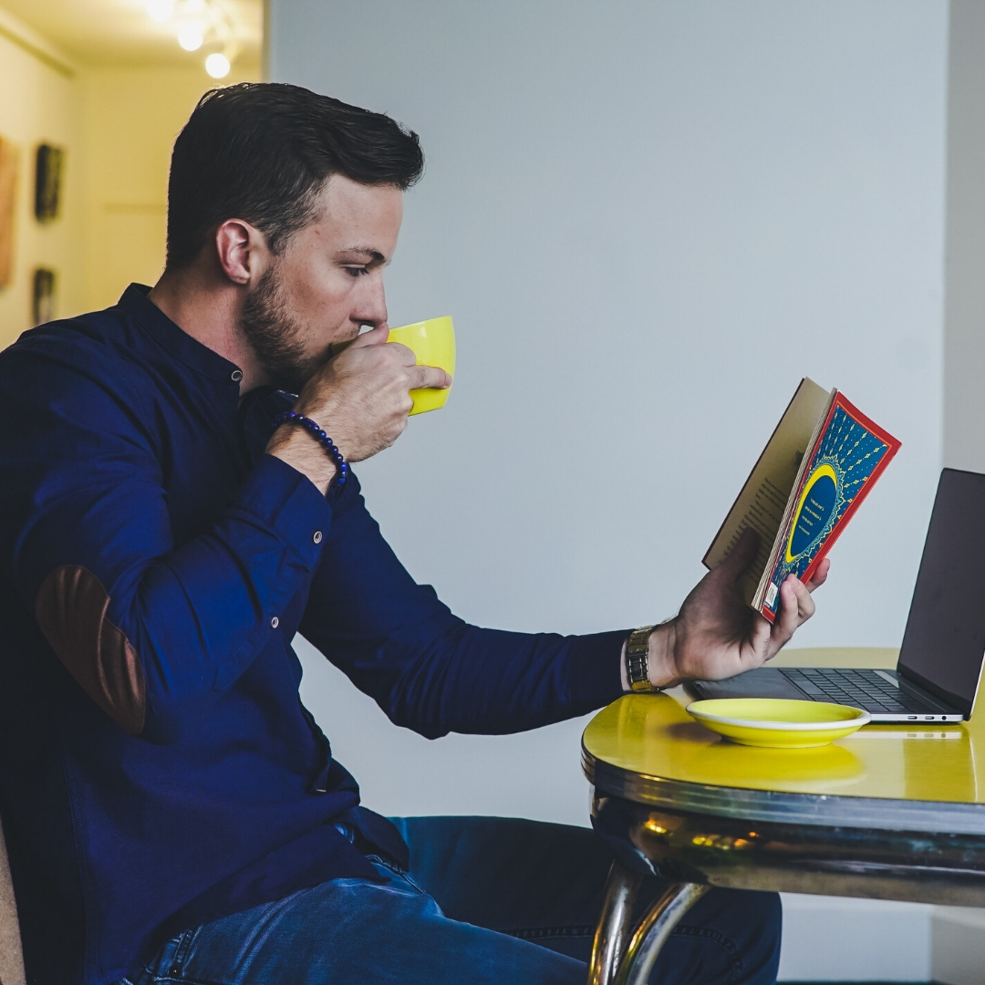 man drinking coffee reading a book