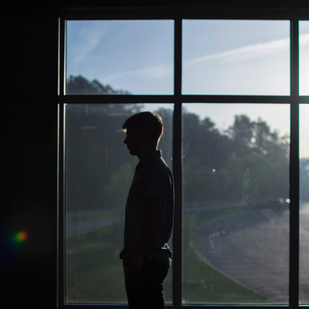 young man staring at wall in front of window