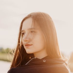 young girl with pensive look on face outside