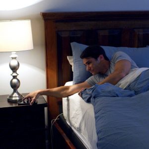 man in bed reaching for phone