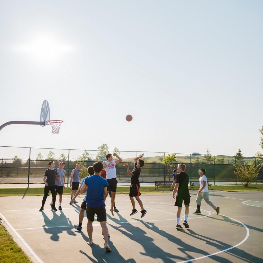 high school boys playing basketball at park