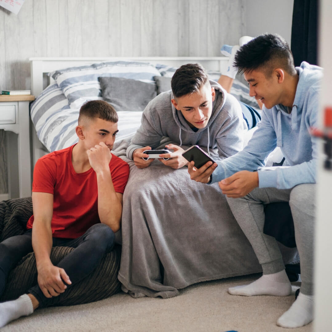teen boys playing video games in bedroom