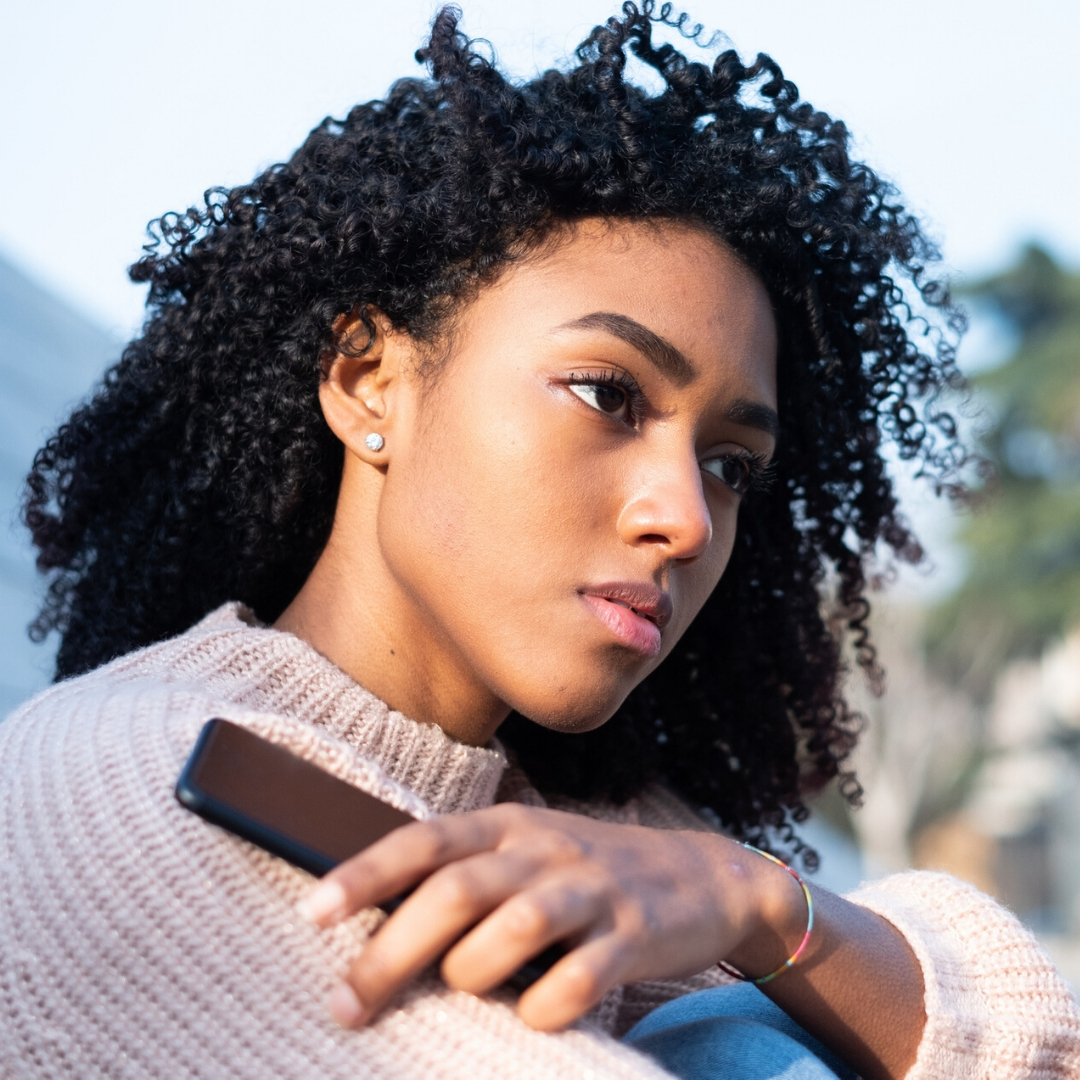 girl with serious look holding phone outside