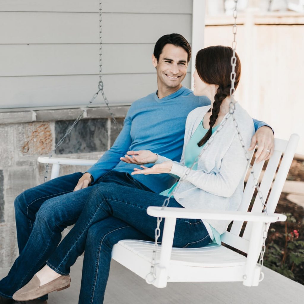 smiling couple talking on porch swing