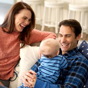 mom and dad smiling at young baby