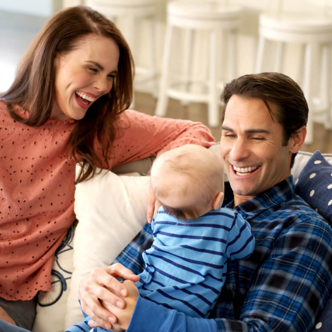 mom and dad smiling at young baby