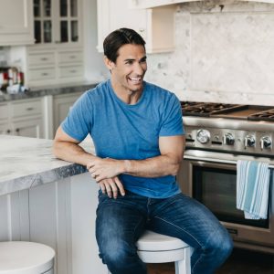 man smiling in kitchen on stool