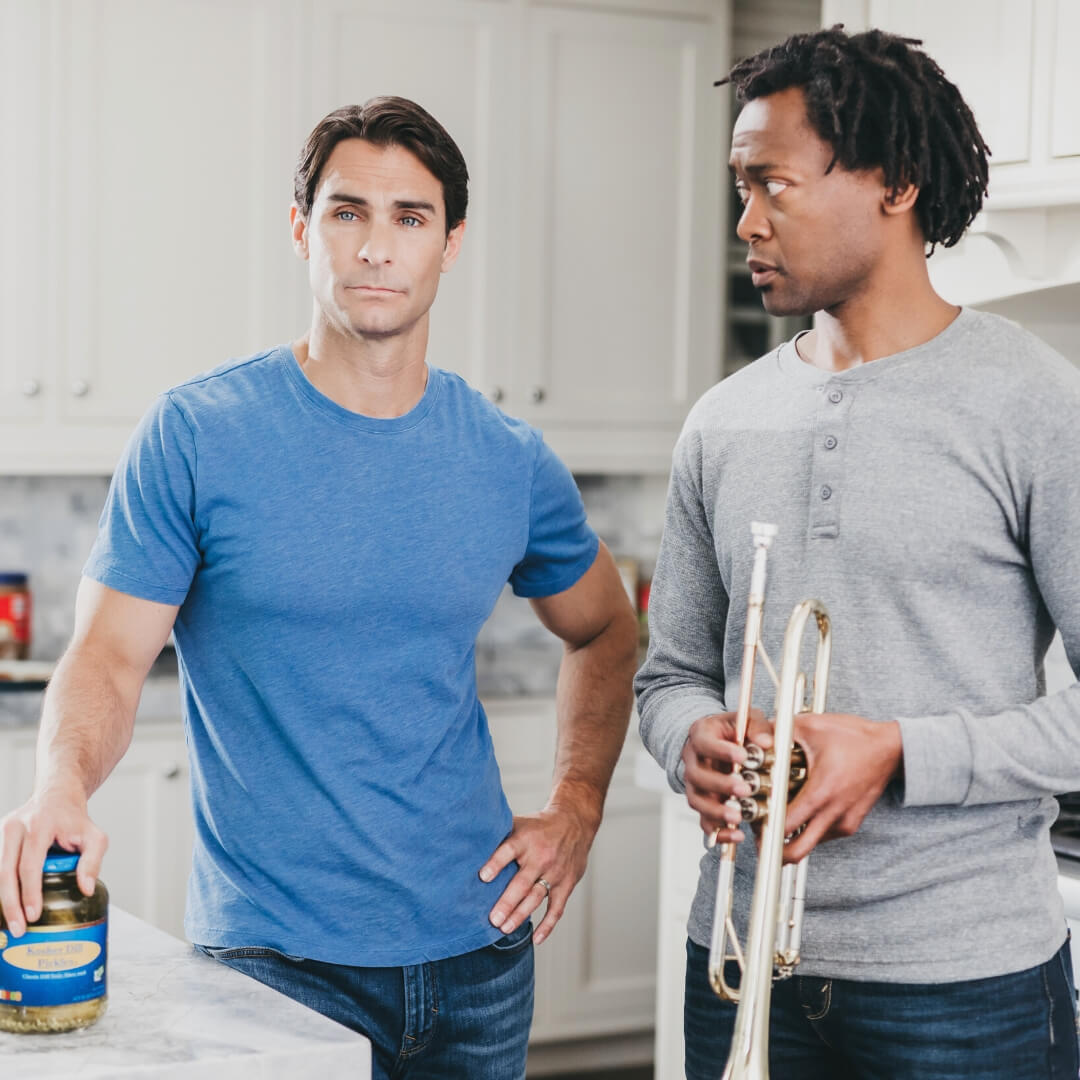 two men in kitchen with pickles and trumpet