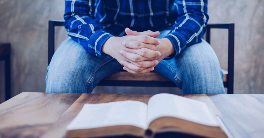 man with open bible and folded hands