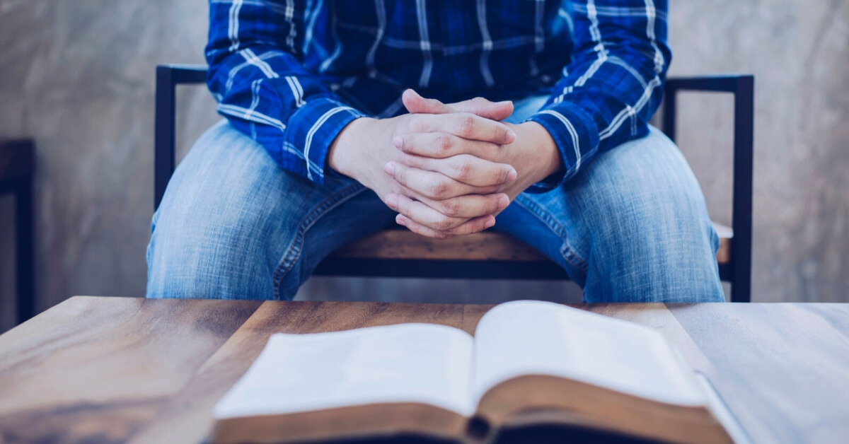 man with open bible and folded hands