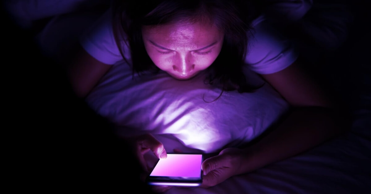woman reading phone in bed