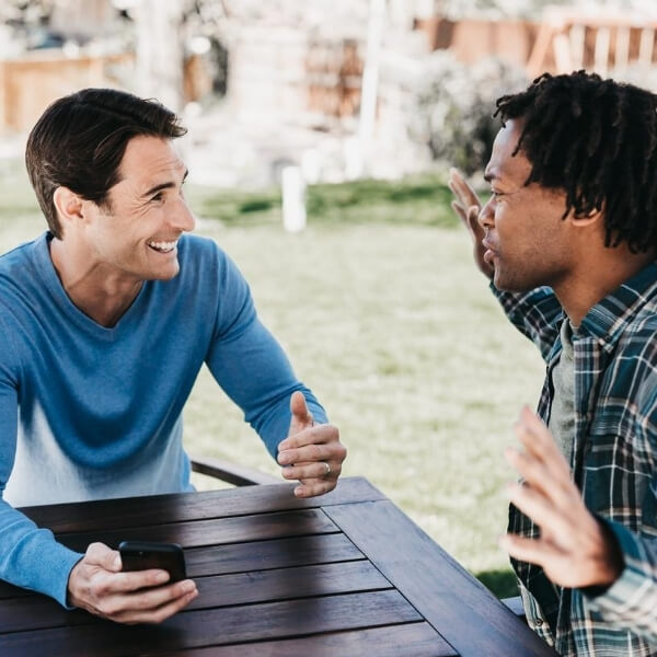 two friends talking excitedly at picnic table