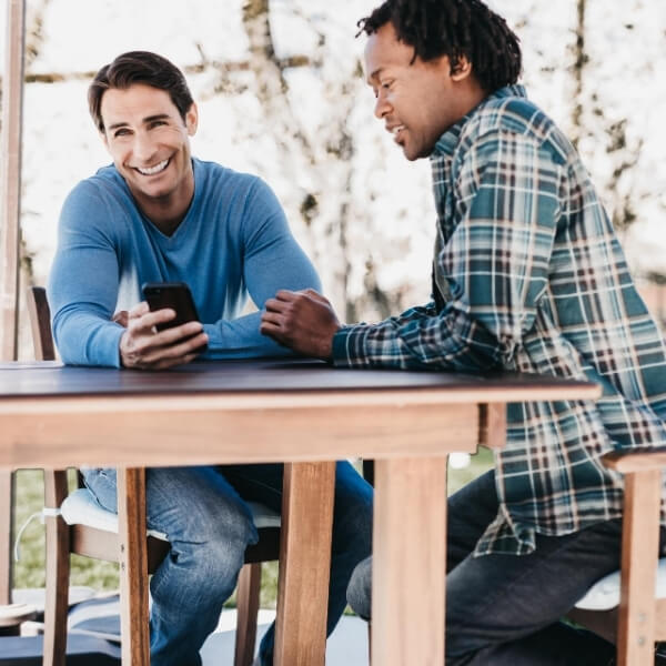 friends laughing at picnic table with phone