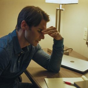 man sitting at desk holding face