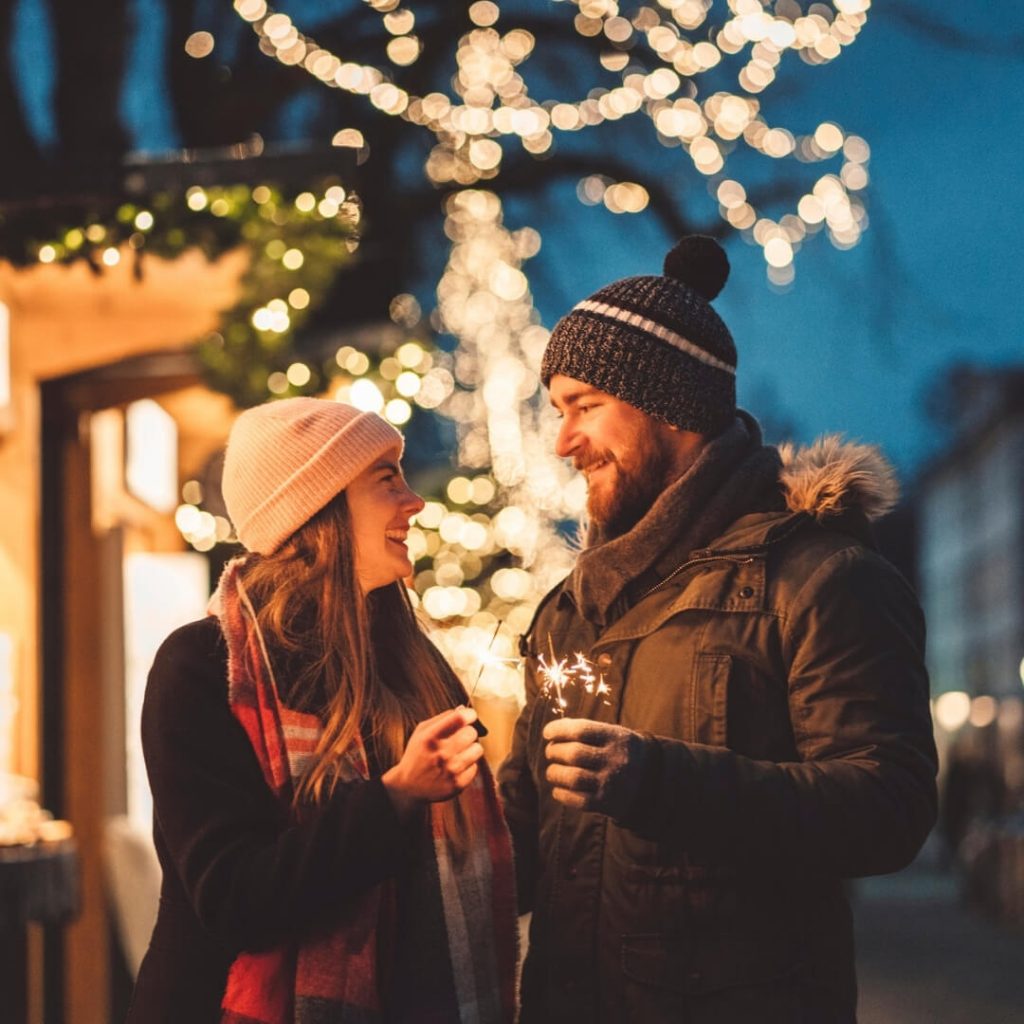 couple bundled up outside with christmas sparklers