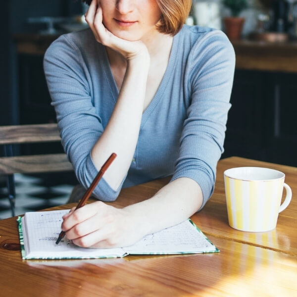 woman writing in journal at coffee shop