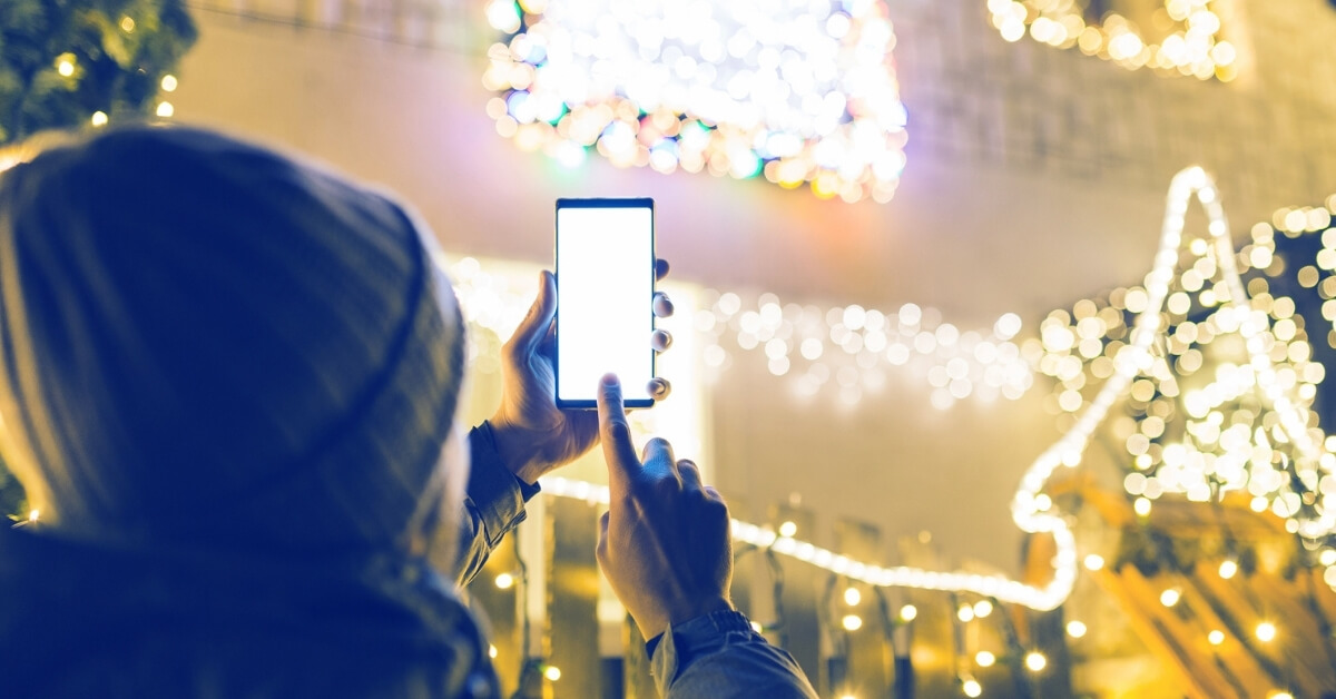 man taking a picture of christmas lights