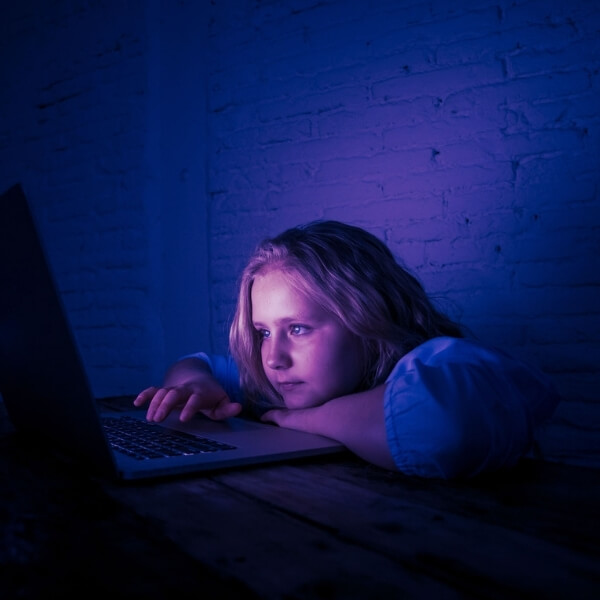 young girl looking at computer screen with purple glow