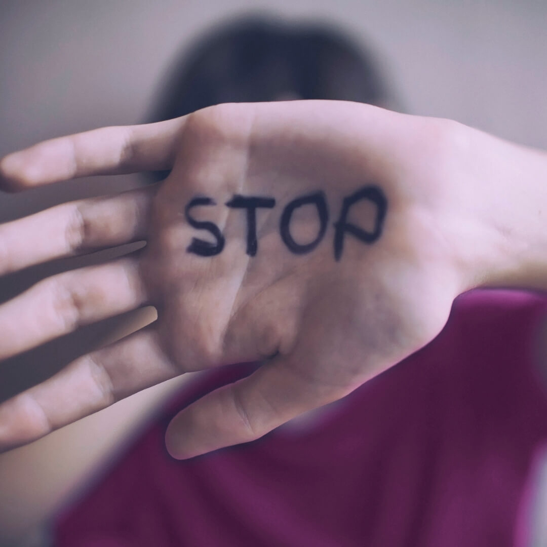 hand with the word "stop" on it held in front of face