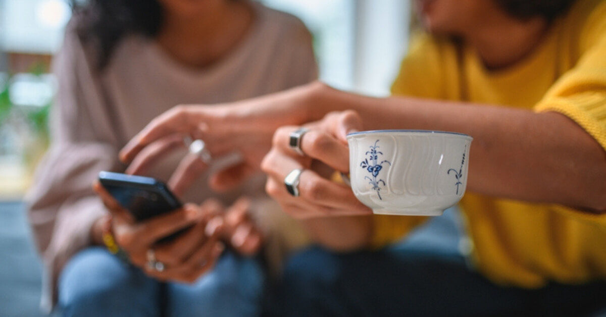 mother and son looking at a phone and drinking coffee