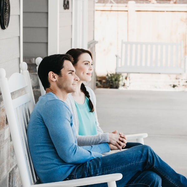 husband and wife sitting next to one another on a porch