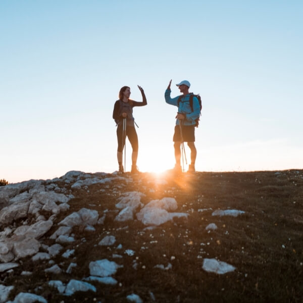 male and female hikers high-fiving on top of a mountain